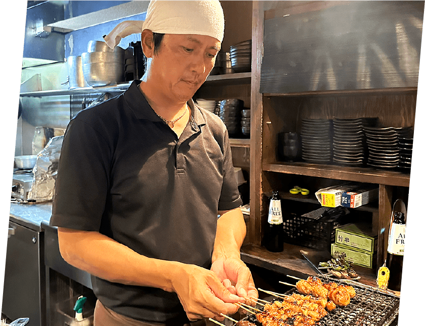 The owner of Yakitori Isao grilling skewers over charcoal at his restaurant